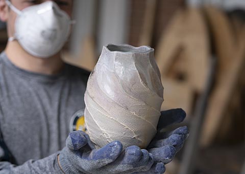 Student displaying ceramic sculpture