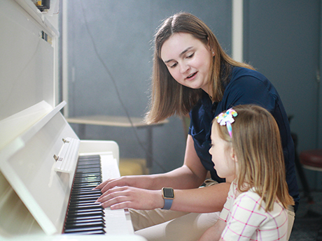 Student working with little girl on the piano
