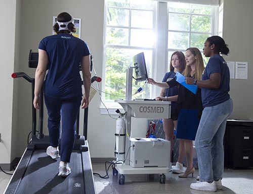 Students and Dr. Knab working with a patient on treadmill