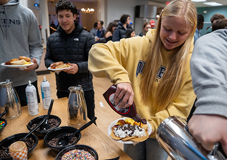 Student adding toppings to pancakes at Exam Break Breakfast