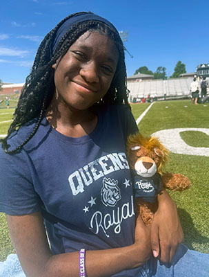 Lauren Lee in Queens tshirt holding a Rex stuffed animal
